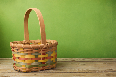 Empty basket on wooden table over grunge green backgroundの写真素材