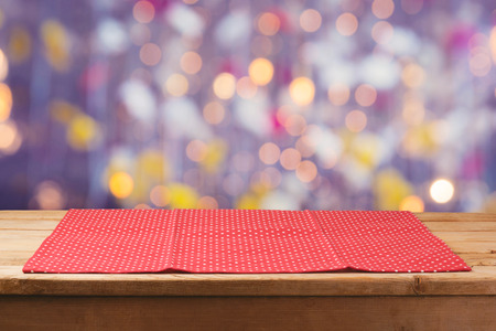 Wooden deck table with polka dots tablecloth over bokeh lights backgroundの写真素材