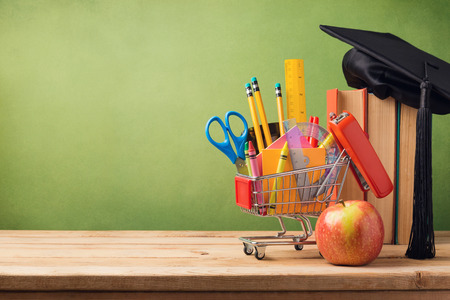 Back to school concept with shopping cart, books and graduation hat