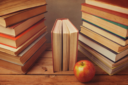 Vintage books with apple on wooden table. Reading a lot of books conceptの写真素材