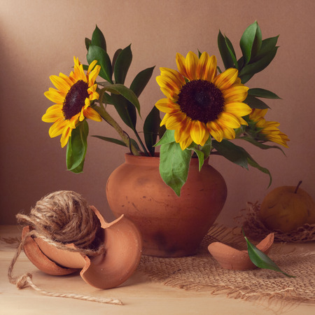 Sunflowers in ceramic vase on wooden tableの写真素材