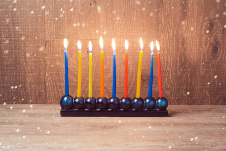 Hanukkah menorah with colorful candles over wooden backgroundの写真素材