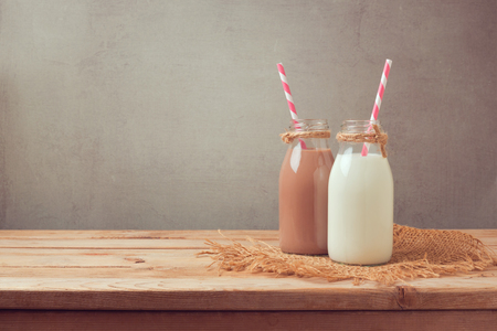 Milk bottle and chocolate milk bottle on wooden table. Healthy eating conceptの写真素材