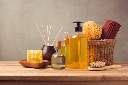 Cosmetic body care and spa products on wooden table over grey background