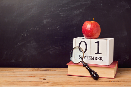 Back to school background with book, apple and calendar over chalkboardの写真素材