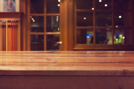 Empty wooden deck table over interior restaurant and bar bokeh background for product montage...