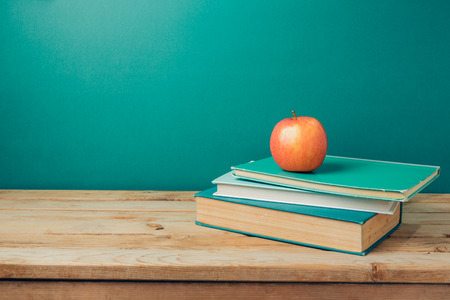 Back to school concept with books and apple on wooden table over green backgroundの写真素材