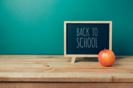 Back to school concept with chalkboard and apple on wooden table over green backgroundの写真素材