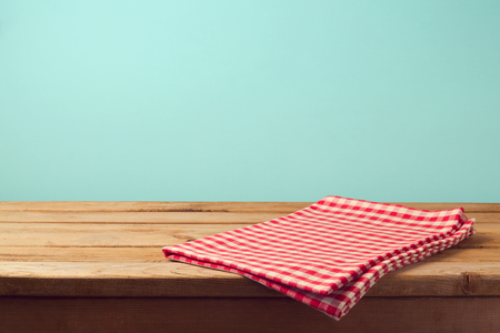 Empty wooden deck table and red checked tablecloth over mint wallpaper backgroundの写真素材