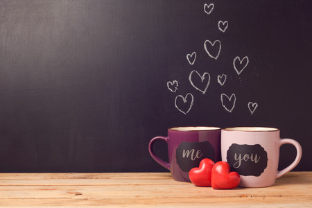 Valentine's day concept with hearts and cups over chalkboard backgroundの写真素材