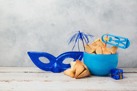 Jewish holiday Purim concept with hamantaschen cookies or hamans ears and carnival mask over rustic backgroundの写真素材