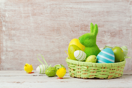 Easter holiday decorations with eggs and bunny in basket over wooden rustic backgroundの写真素材