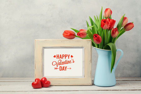Valentines day concept with tulip flowers and photo frame over rustic backgroundの写真素材