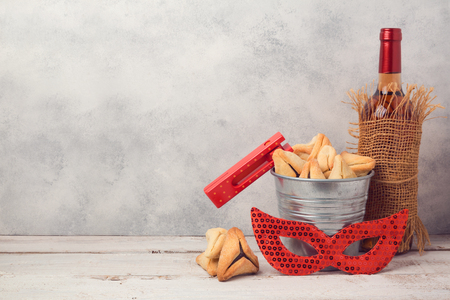 Jewish holiday Purim concept with hamantaschen cookies or hamans ears, carnival mask and wine bottle over rustic backgroundの写真素材