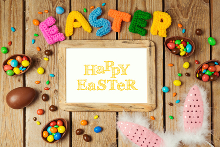 Easter holiday concept with chocolate eggs and photo frame on wooden background. Top view from aboveの写真素材