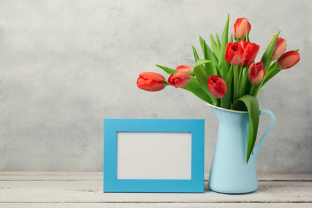 Women day concept, 8th of March with tulip flowers and photo frame on wooden tableの写真素材