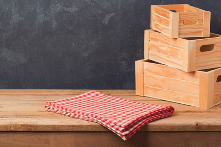 Empty table with tablecloth and wooden boxes over dark blackboard background for product montage...