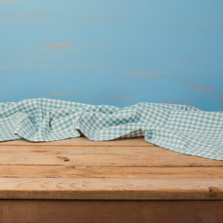 Empty wooden table with checked blue tablecloth over rustic painted wall for product montage displayの写真素材