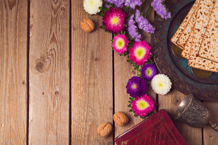 Jewish holiday Passover background with matza, seder plate and spring flowers. View from above