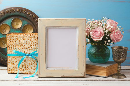 Jewish holiday Passover Pesah concept with poster photo frame, matzoh and rose flowers bouquetの写真素材