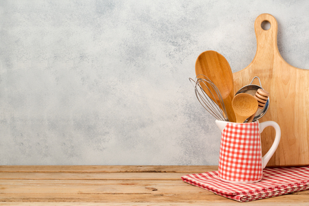 Kitchen utensils and cutting board on wooden table over rustic background with copy spaceの写真素材