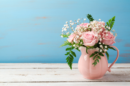 Rose flower bouquet in pink vase over wooden background with copy spaceの写真素材