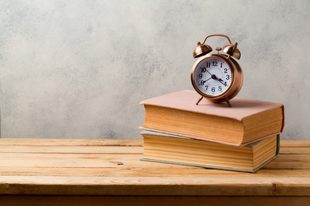 Retro alarm clock and vintage books on wooden table with copy spaceの写真素材