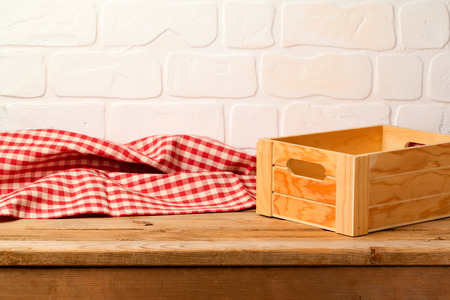 Empty wooden deck table with box and tablecloth over brick wall backgroundの写真素材