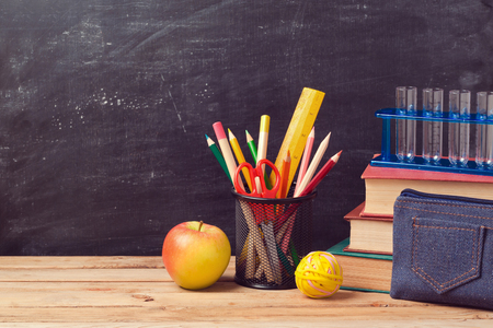 Back to school background with books, pencils and apple over chalkboardの写真素材