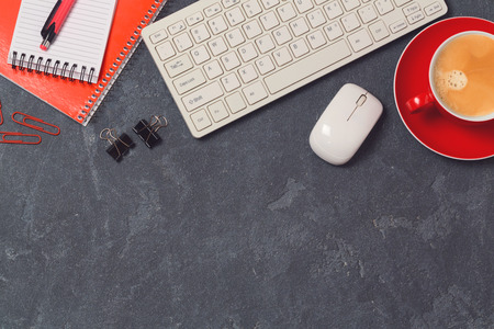 Office desk with computer, notebooks and coffee cup over blackboard background. Top viewの写真素材