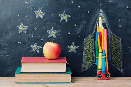 Back to school concept with rocket made from pencils and books over chalkboard backgroundの写真素材