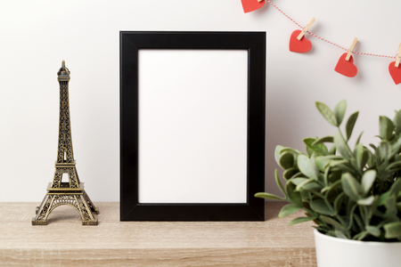 Black frame mock up with Effiel tower, plant and heart shape garland. Modern stylish interior background for social media and marketing.の写真素材