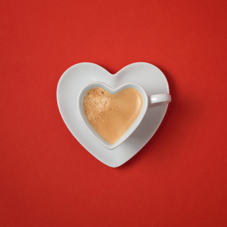 Heart shape coffee cup over red background. View from aboveの写真素材