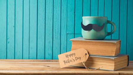 Happy Fathers day concept with coffee cup, mustache and books over wooden backgroundの写真素材