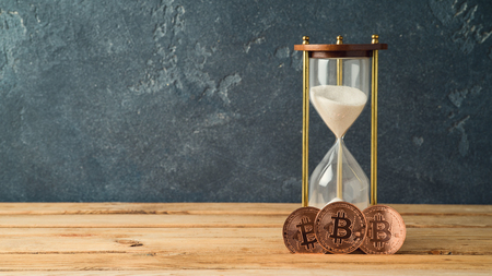 Bitcoin coin and hourglass on wooden table Cryptocurrency conceptの写真素材