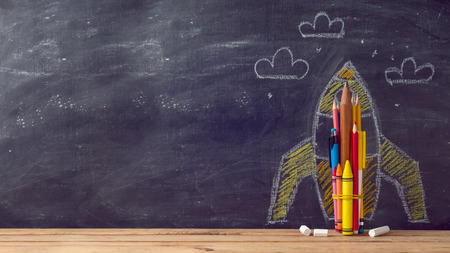 Back to school background with rocket sketch and pencils over chalkboardの写真素材
