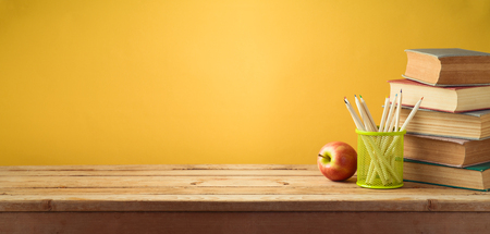 Back to school background with pencils, apple and old books over yellow wallの写真素材