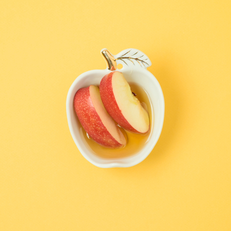 Honey and apple on yellow background. Minimal concept. Flat layの写真素材