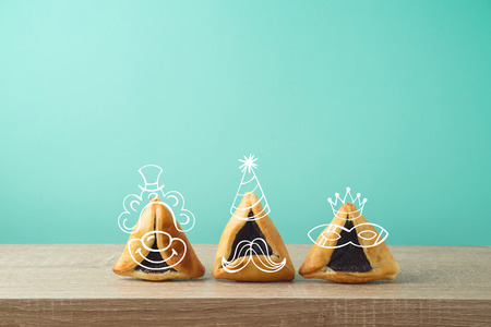 Jewish holiday Purim concept with cute hamantaschen cookies characters on wooden tableの写真素材