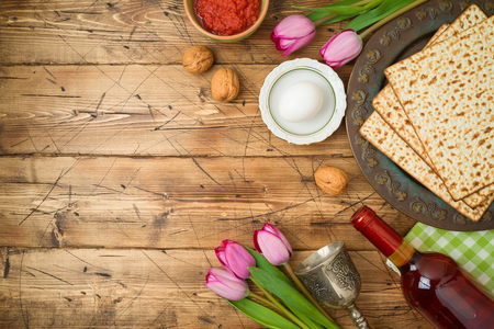 Jewish holiday Passover background with matzo, seder plate, wine and tulip flowers on wooden table. Top view from above. の写真素材