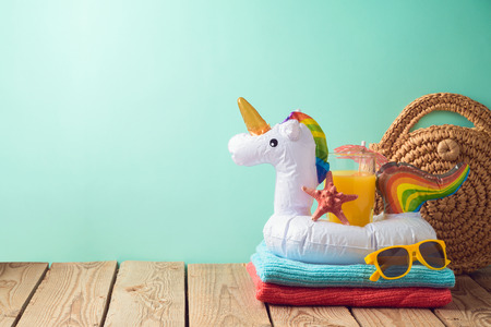 Summer vacation background with orange juice and unicorn pool float on wooden tableの写真素材