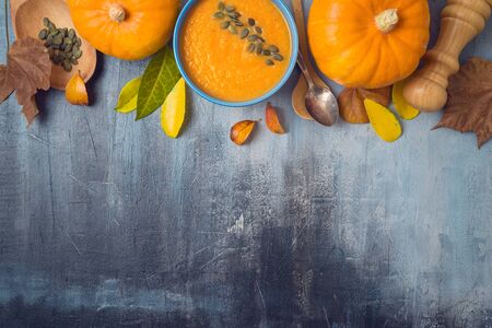 Pumpkin soup on rustic background. Autumn concept with pumpkin and fall leaves. Top view from aboveの写真素材