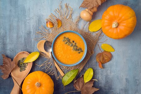 Pumpkin soup on rustic background. Autumn concept with pumpkin and fall leaves. Top view from aboveの写真素材