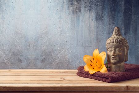 Buddha statue, flowers and towel on wooden table over dark backgroundの写真素材