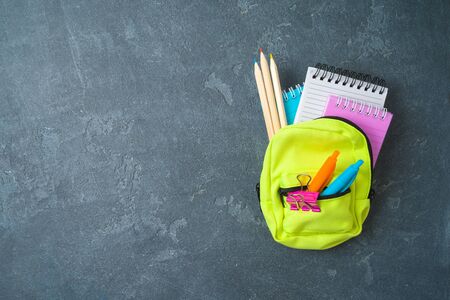 Back to school background with small bag backpack and school supplies on wooden table. Top view from...