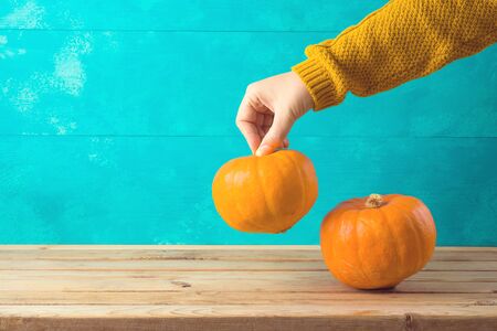 Autumn background with pumpkin on wooden table and woman hand.の写真素材