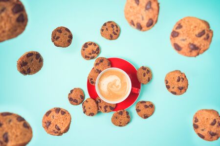 Coffee cup with flying cookies over blue background. Top view from aboveの写真素材