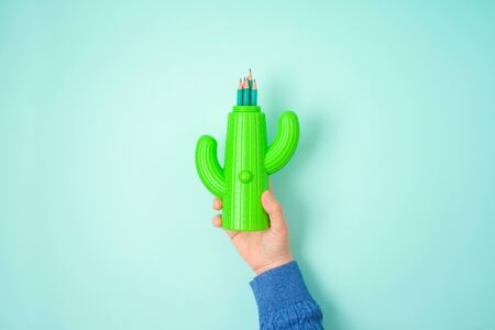 Back to school creative concept with hand holding pencils over blue background. Top view from aboveの写真素材