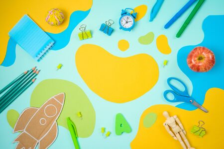 Back to school concept with school supplies and paper flowing shapes background. Top view from above