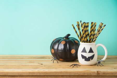 Halloween holiday concept with jack o lantern cup and black pumpkin decor on wooden tableの写真素材